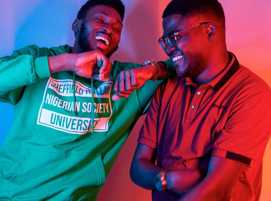 Two Black students laughing and leaning on each other