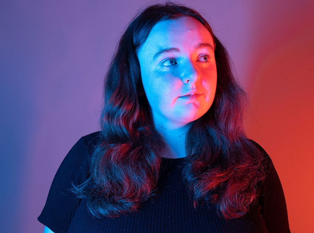 A student lit up by blue lights against a studio background