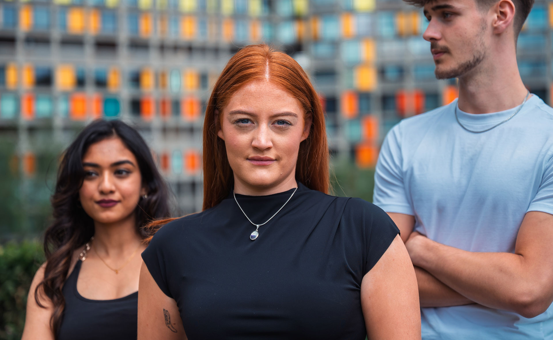 Three students standing in front of a contemporary building
