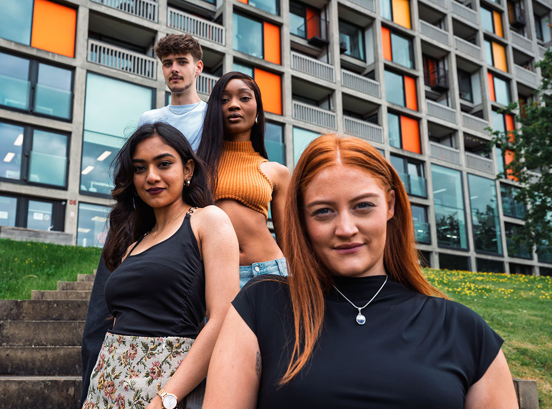 Four students pose in front of a contemporary Sheffield building.