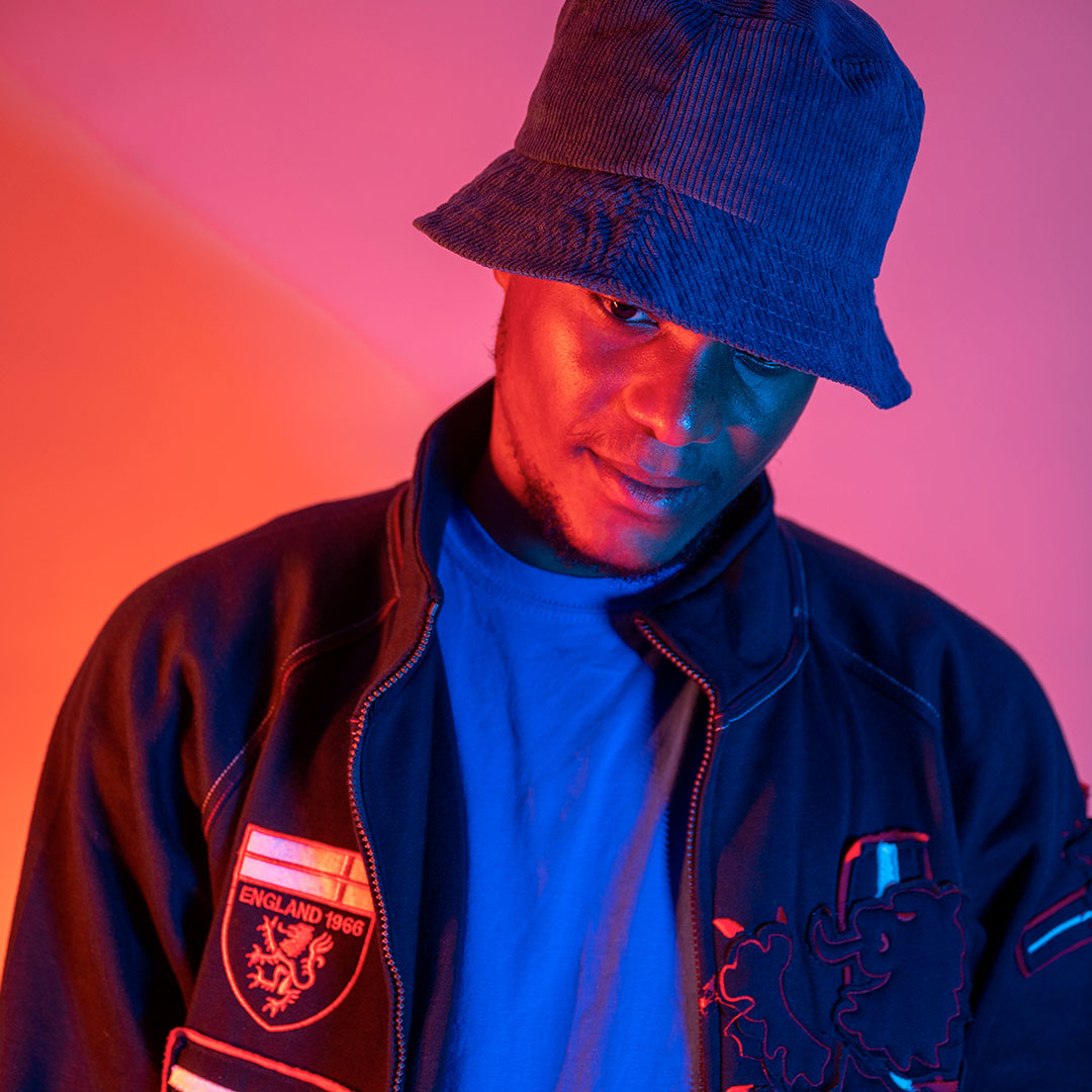 A student wearing a hat and looking towards the floor