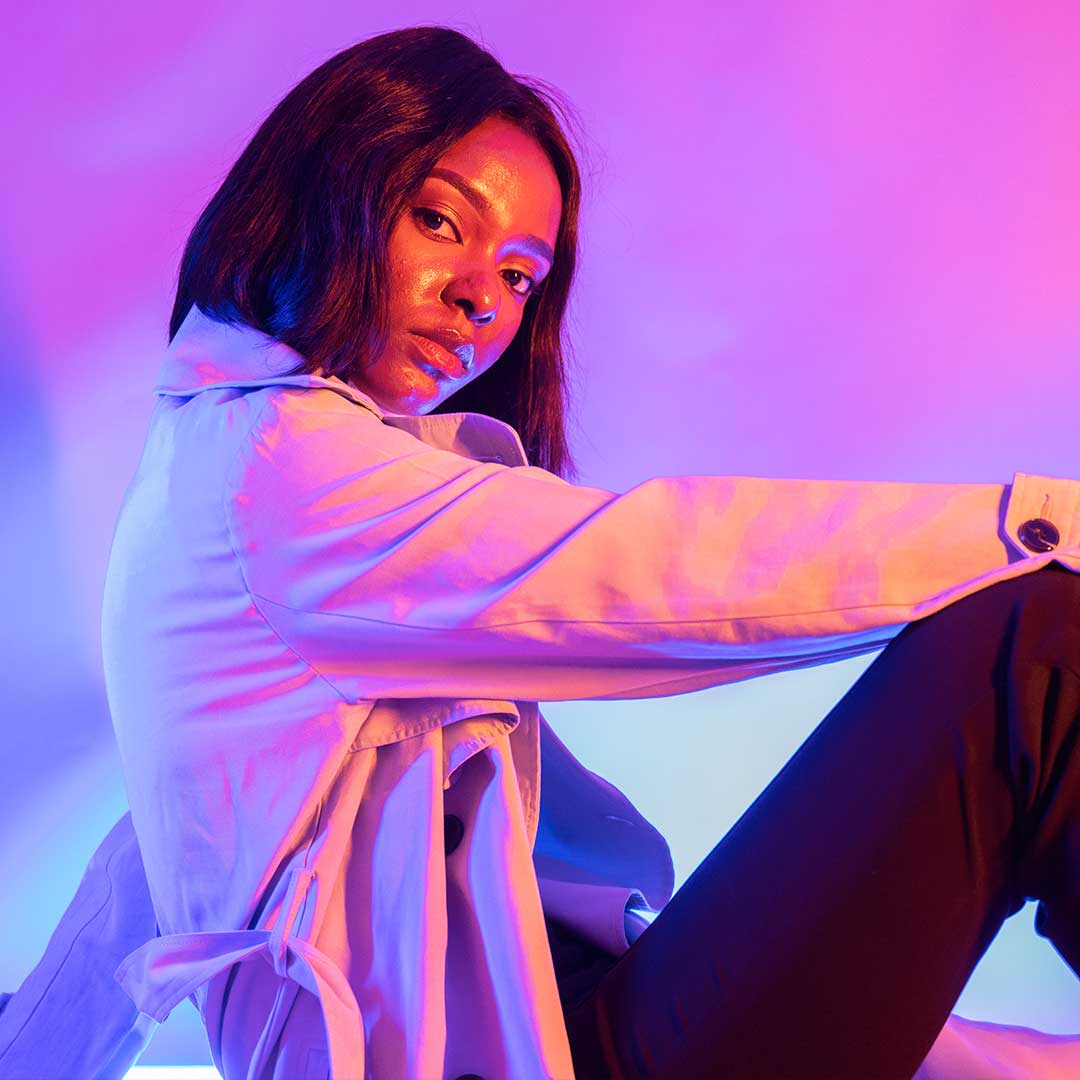 A student sat on the floor facing perpendicular to the camera, wearing a white coat