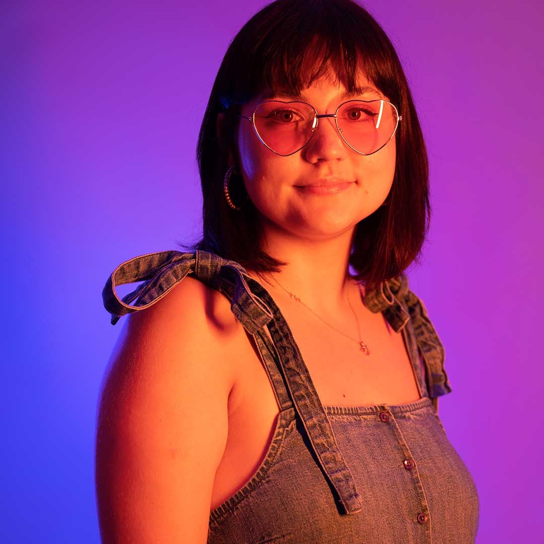 A student smiling at the camera wearing heart shaped glasses