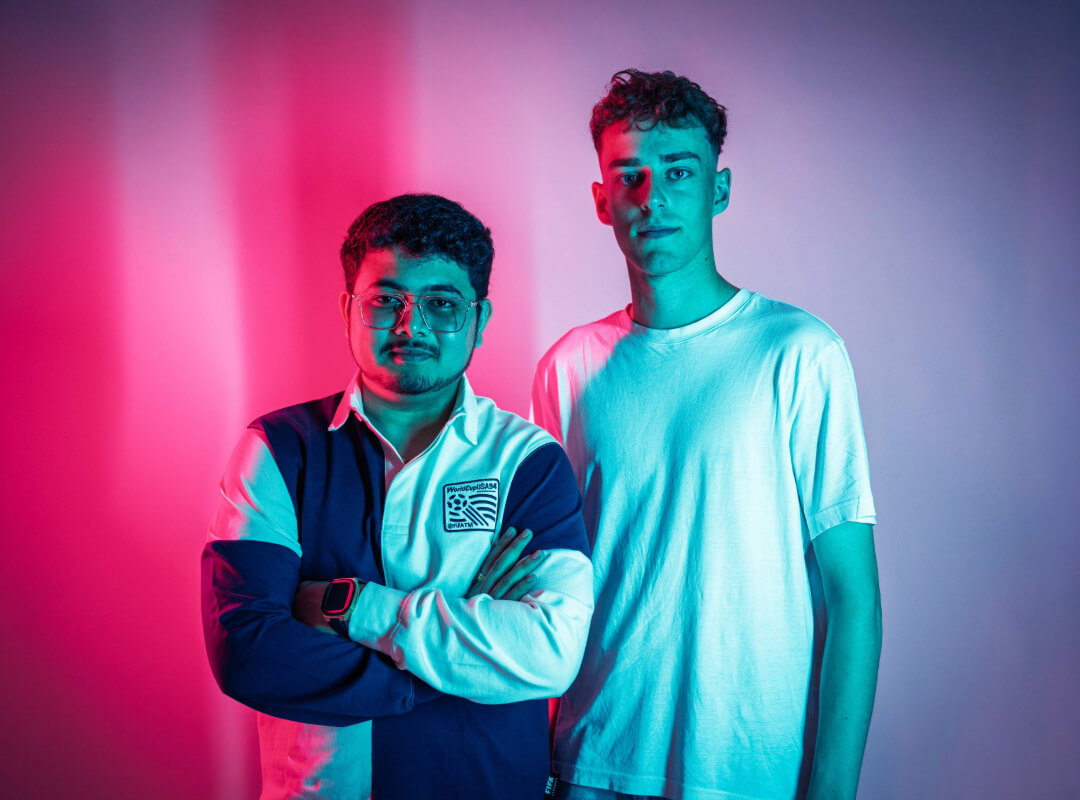 Two students standing side-by-side, one with their arms folded.