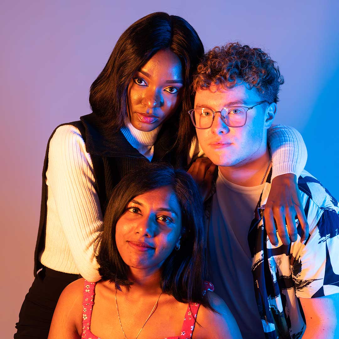 Three students looking into the camera with their arms around each other's shoulders