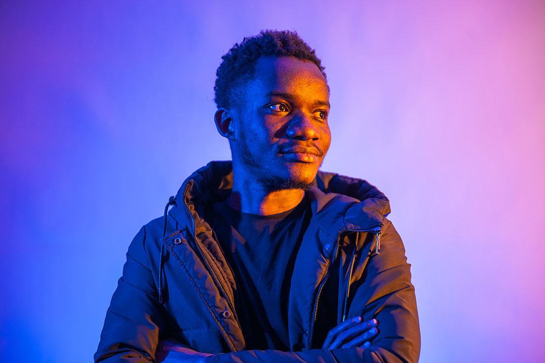 Student looking to the side of the camera, light up by purple neon lights