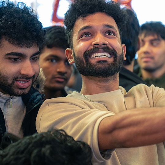 Student surrounded by friends looking up with a big excited grin.