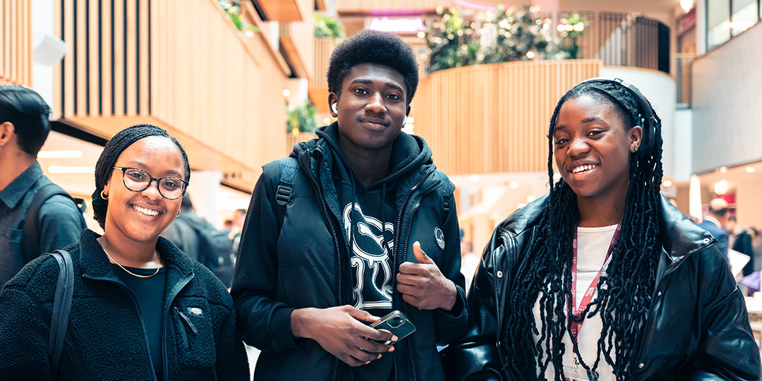 Three students stood next to each other and smiling at the camera.
