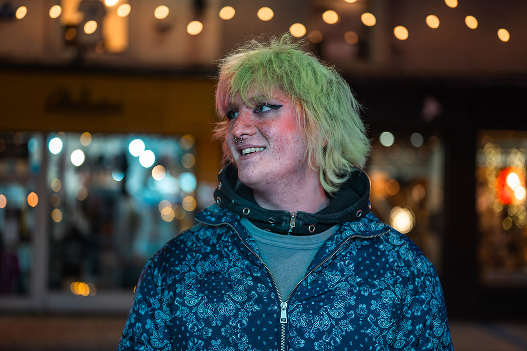 Student with green hair smiling into distance