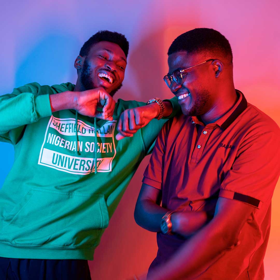 Two Black students laughing and leaning on each other
