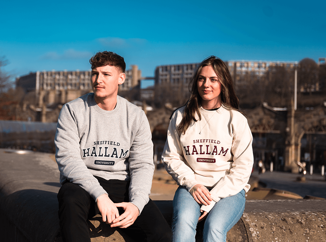 Two students sat on a wall wearing Hallam sweatshirts.
