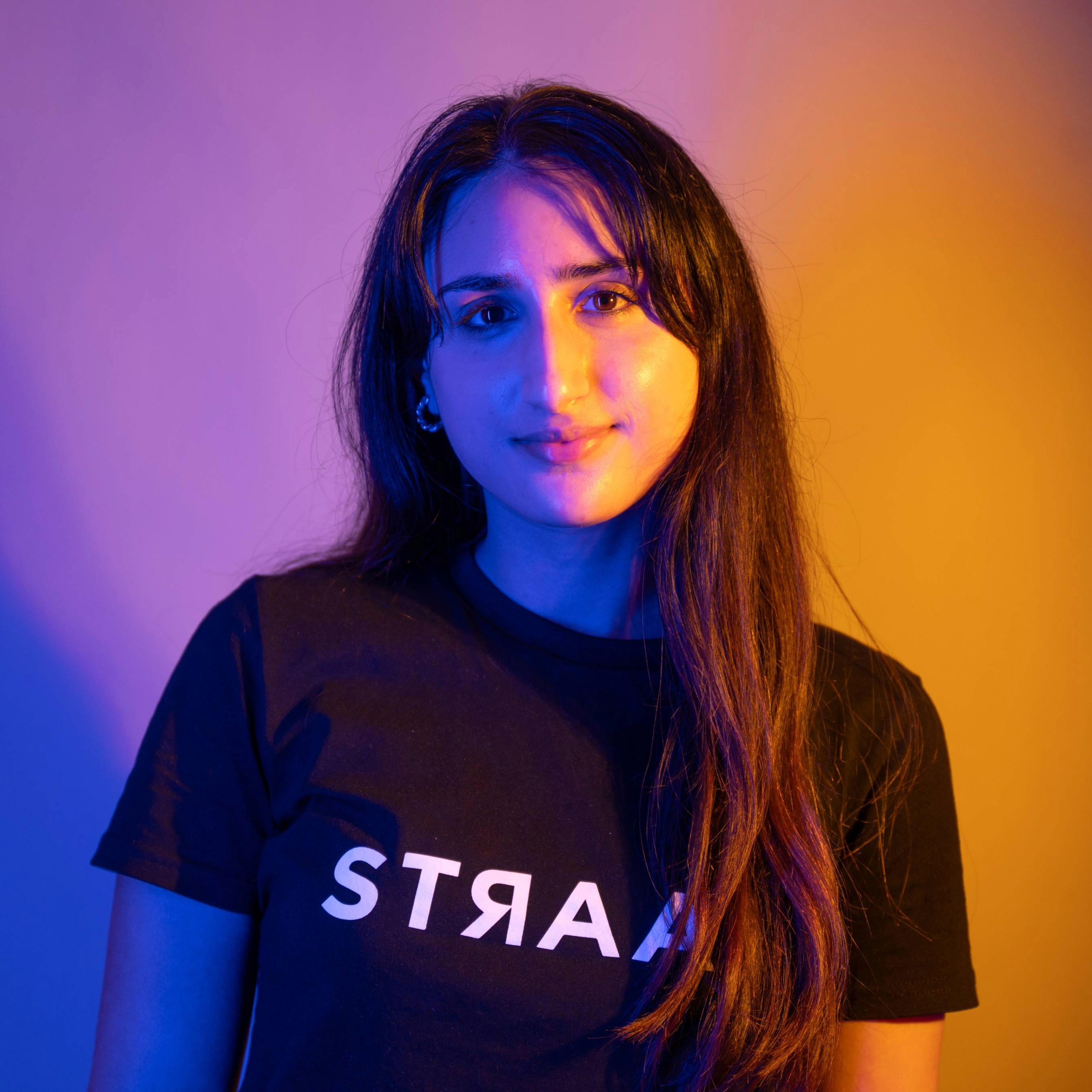 A student wearing a black T-shirt on an orange and pruple background.