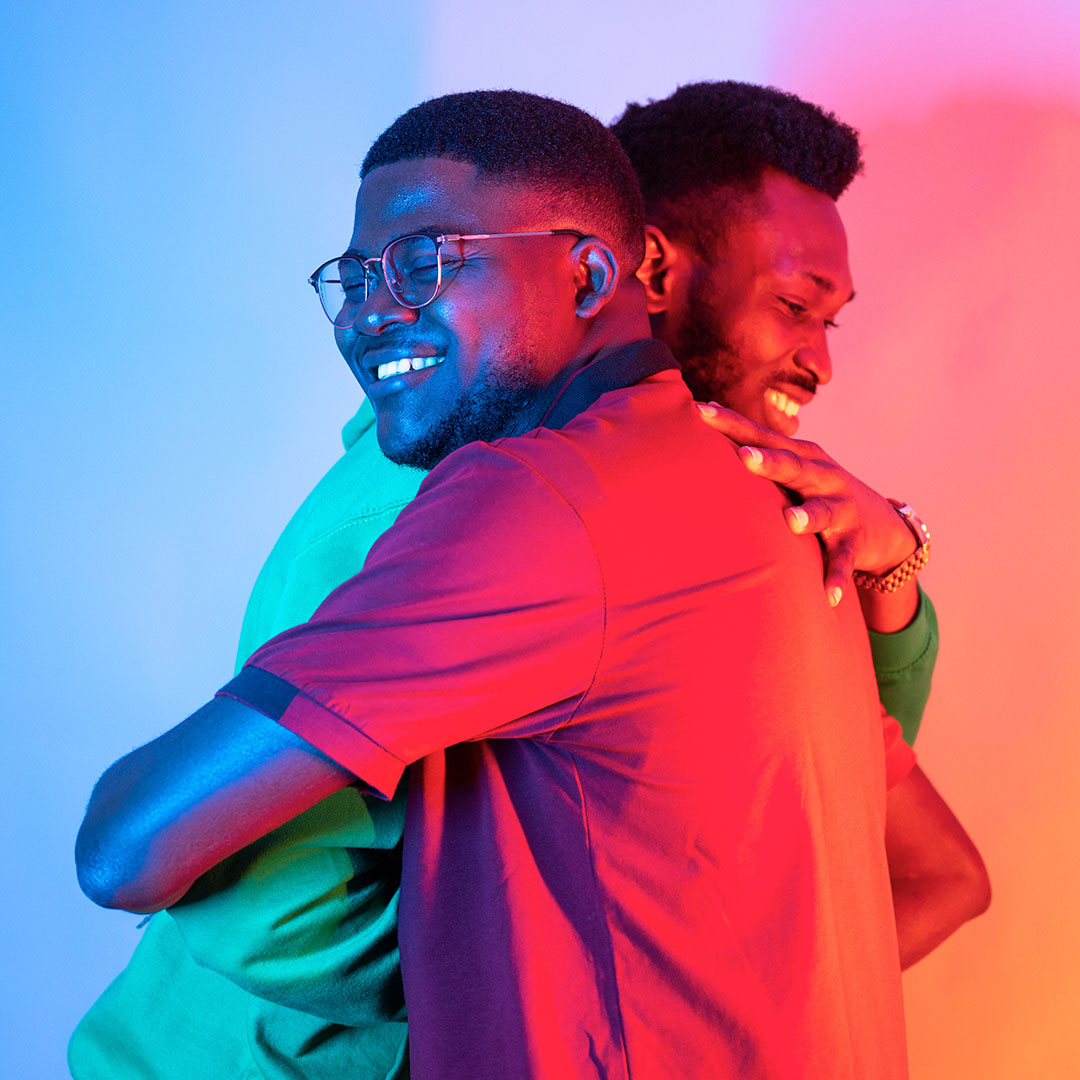 Two students hugging in neon lighting