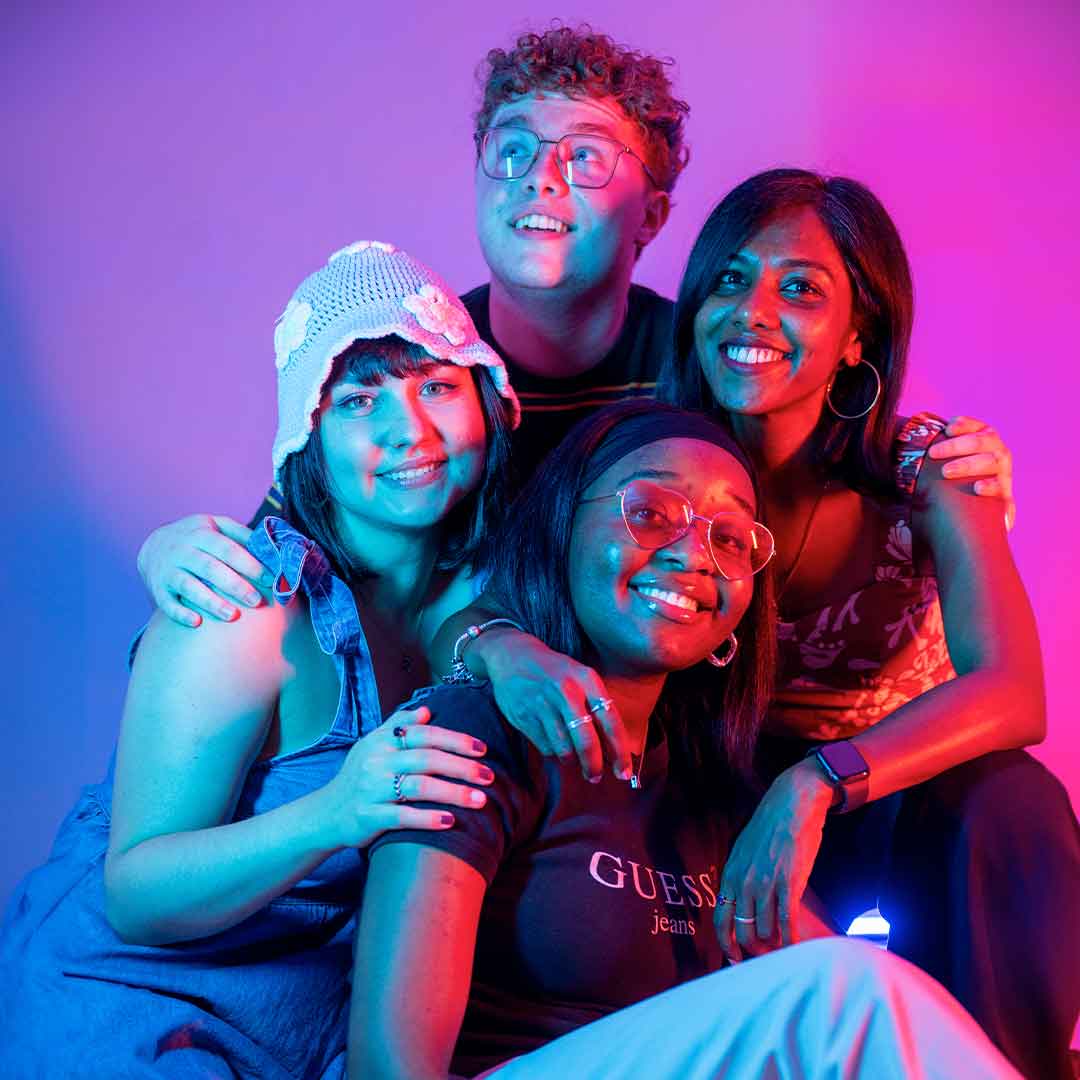 Four students laughing at the camera with their arms around each other