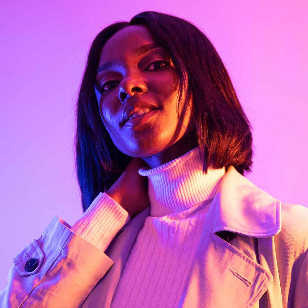 A student wearing a white turtleneck and looking at the camera with her chin tilted up confidently