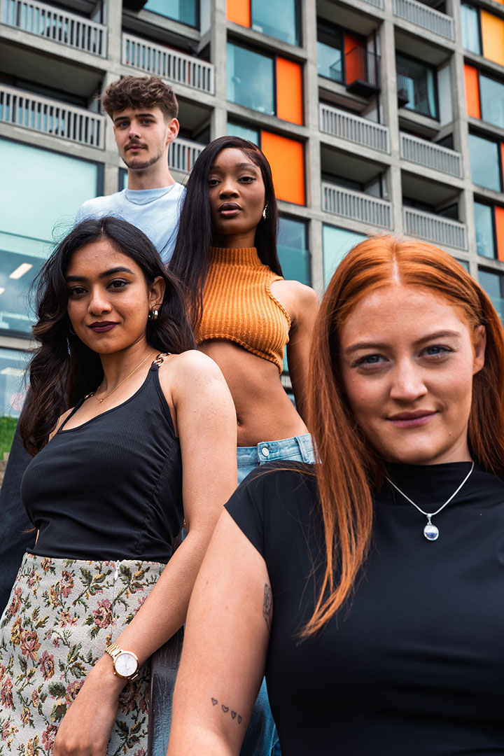Four students pose in front of a contemporary Sheffield building.